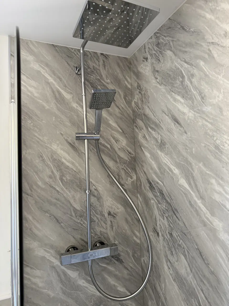 Chrome rainfall shower on grey marble-effect wall panels