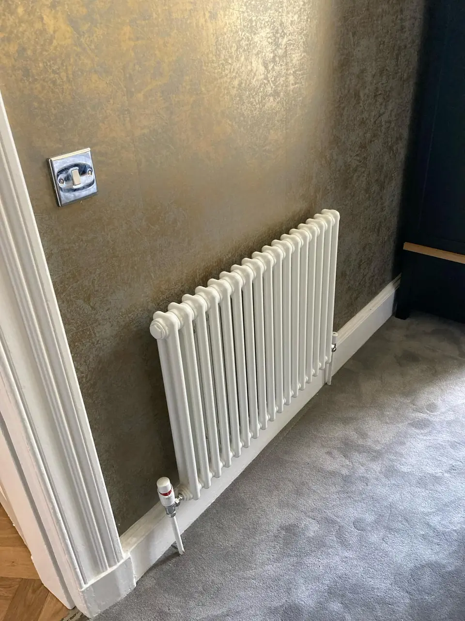 White column radiator fitted against a textured gold feature wall