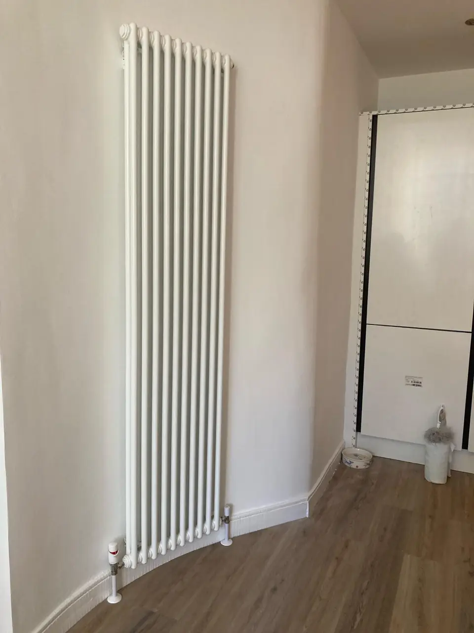 Tall vertical column radiator fitted in a bright hallway