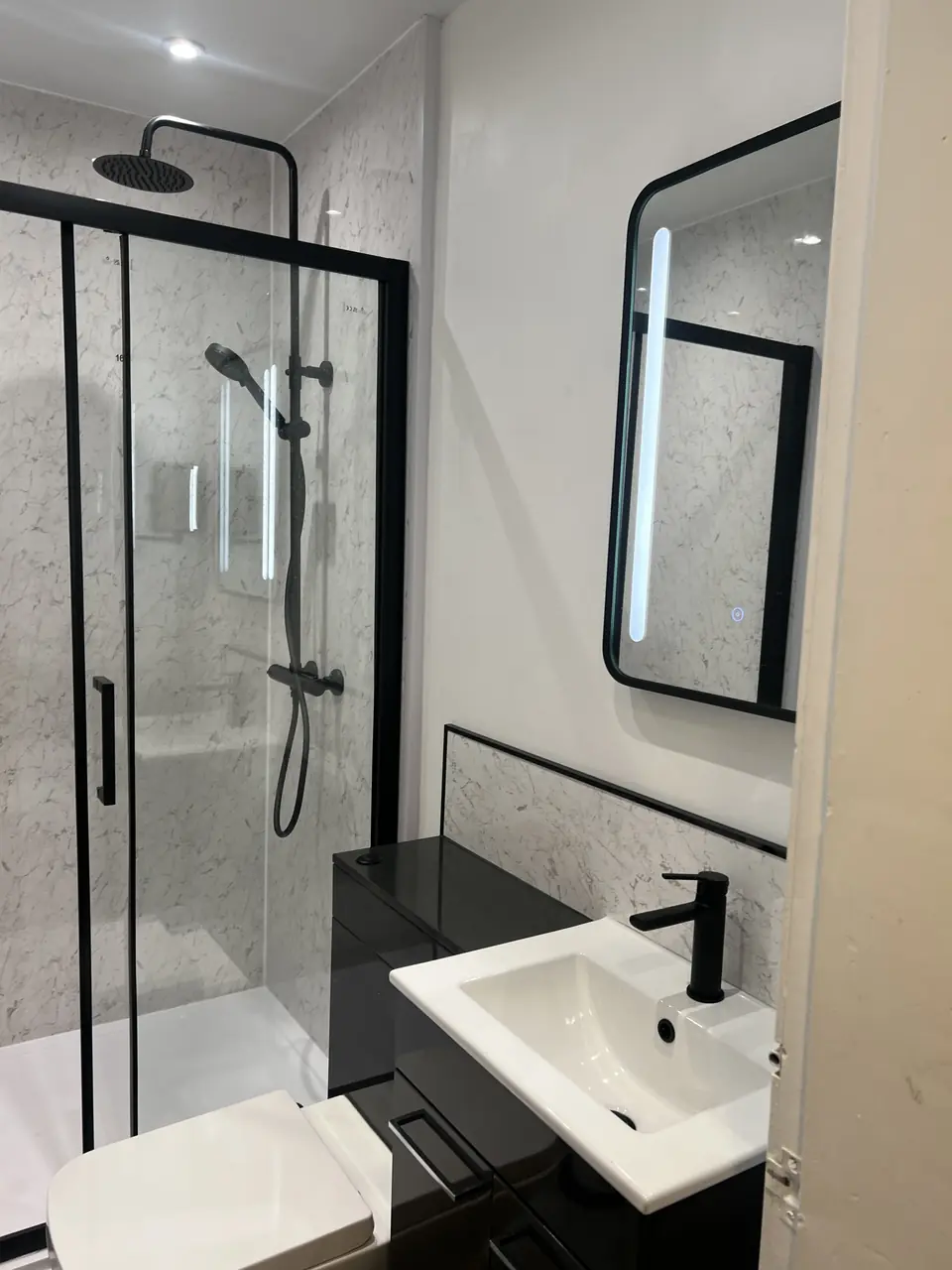 Black framed shower enclosure, illuminated mirror and black vanity unit